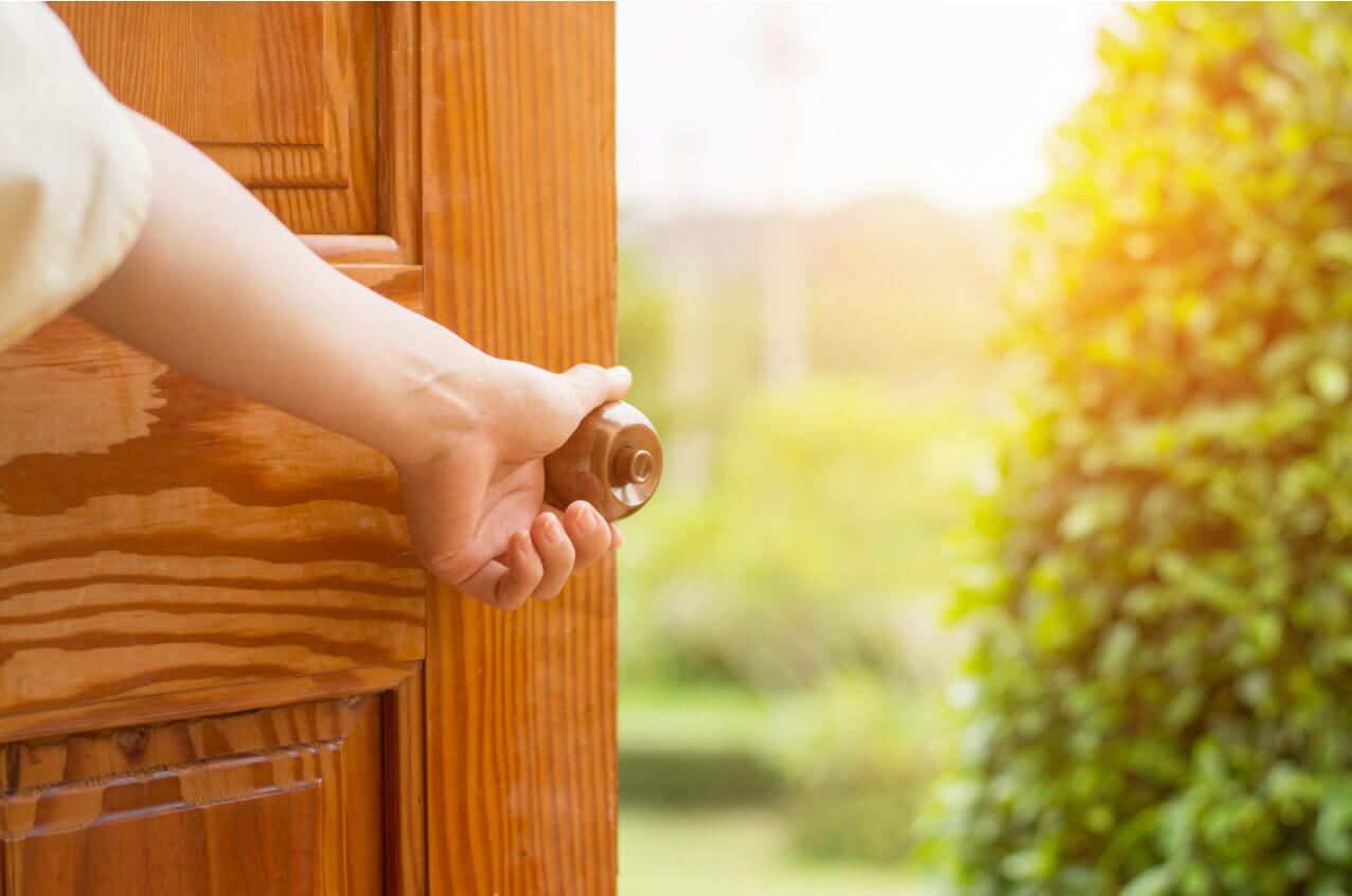 Une personne ouvre la porte vers l’extérieur tout ensoleillé