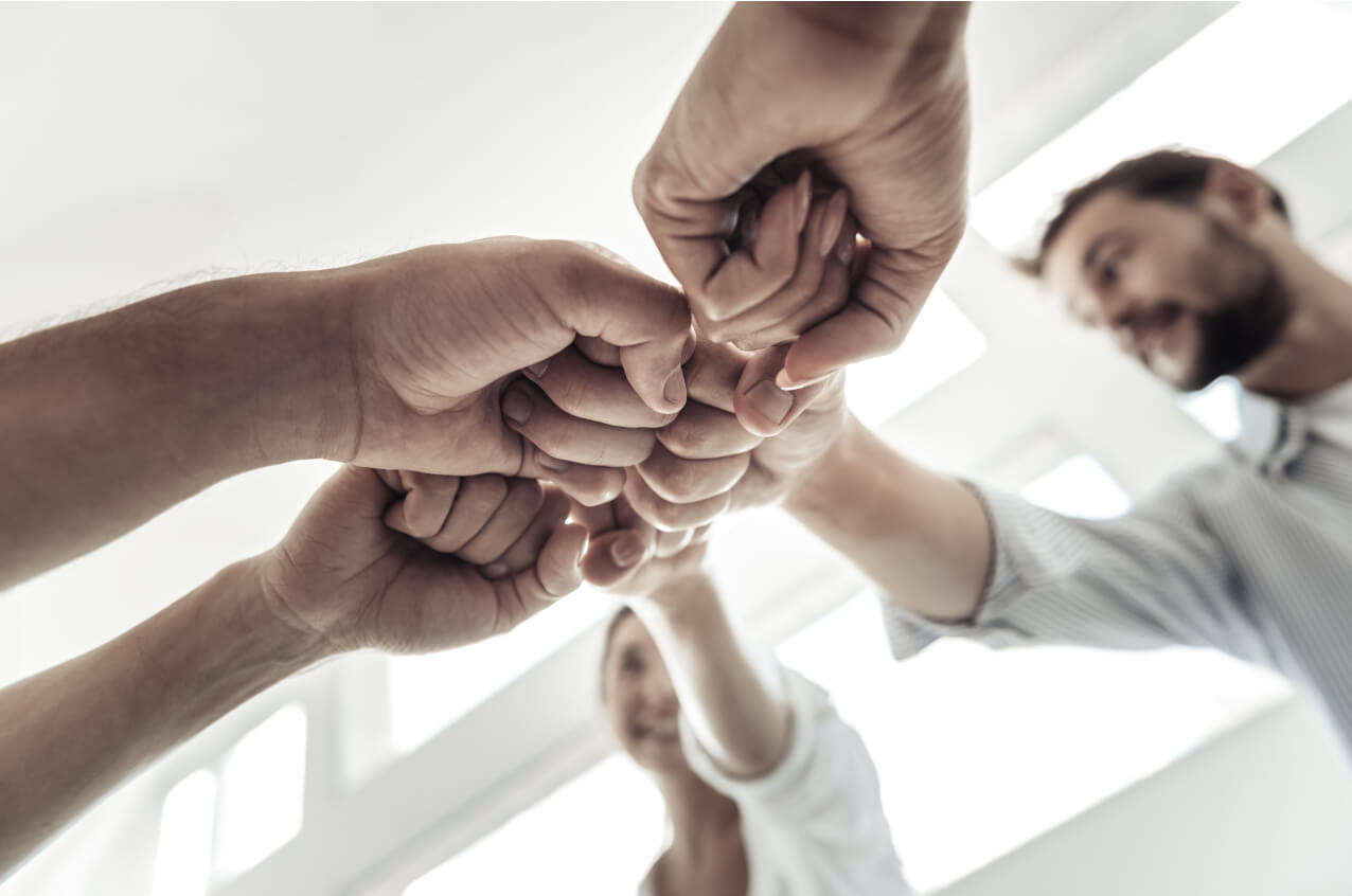 Un groupe de personnes joint leur poing en guise d’entraide et d’encouragement