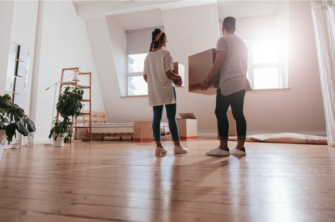 Une femme parle à un homme avec une boite de déménagement dans une nouvelle chambre